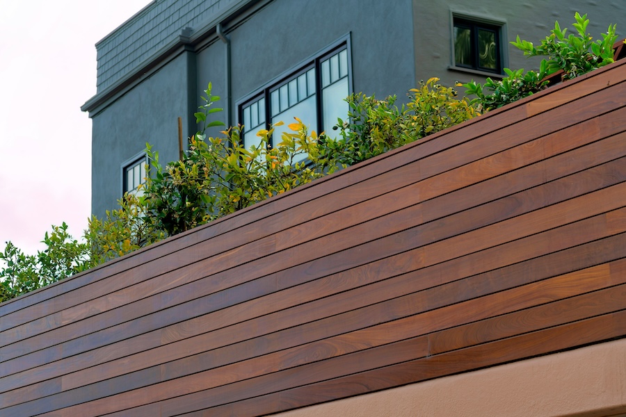 Stained timber slatted privacy wall with grey home in the background